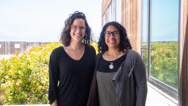 Melissa Cronin and Erika Zavaleta stand on a sunny balcony