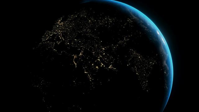A view of the earth from space at night above Africa, Europe and India, with a blue glow on the right side of the globe. 