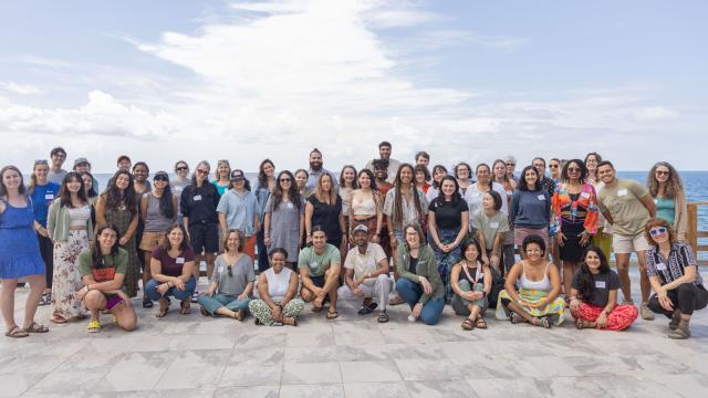 a group photo of fellowship to friendship attendees on the ocean patio with a blue sky and clouds in the background