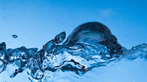 A close up of a wave of clear water on a blue background