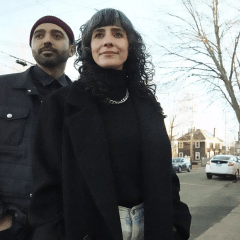 Bruni and David Pizarro stand on a street with a tree in the background