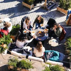 A group of people sit around a circular table on an outdoor patio, eating. 