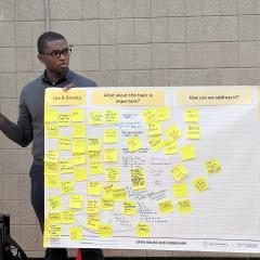 Doug McPherson holds a poster full of post it notes at a community meeting.