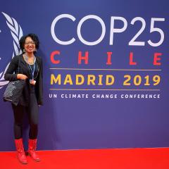 Switzer Fellow Frances Roberts Gregory standing next to the COP25 Banner.