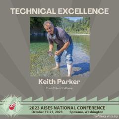A picture of Keith standing in Blue Creek, leaning over, holding some sediment, and smiling. Text reads: Technical Excellent: Keith Parker, Yurok Tribe of California. 2023 AISES National Conference Oct 19-21, 2023, Spokane, WA. Conference.aises.org 