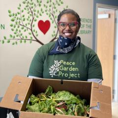 Michelle Lewis stands with a box full of produce.