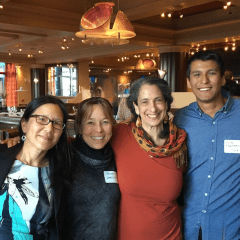 A group of fellows is smiling with their arms around each other at a restaurant.