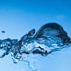 A close up of a wave of clear water on a blue background