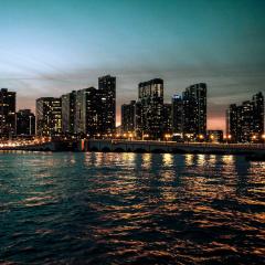 Sunset behind tall buildings along the Miami, FL coast, seen across water.