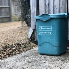 A food waste bin sits next to a building