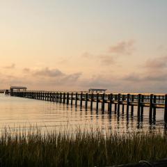 The Chesapeake Bay reflects the sunset, with a dock extending out into the water and grasses in the foreground.