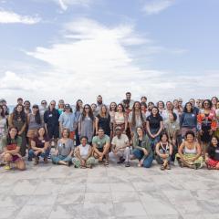 Switzer Fellows pose with big smiles on the beach with a cloudy sky.