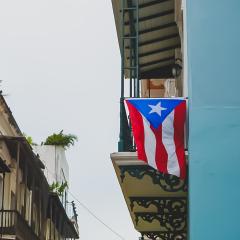 A Puerto Rican flag hangs from an apartment balcony