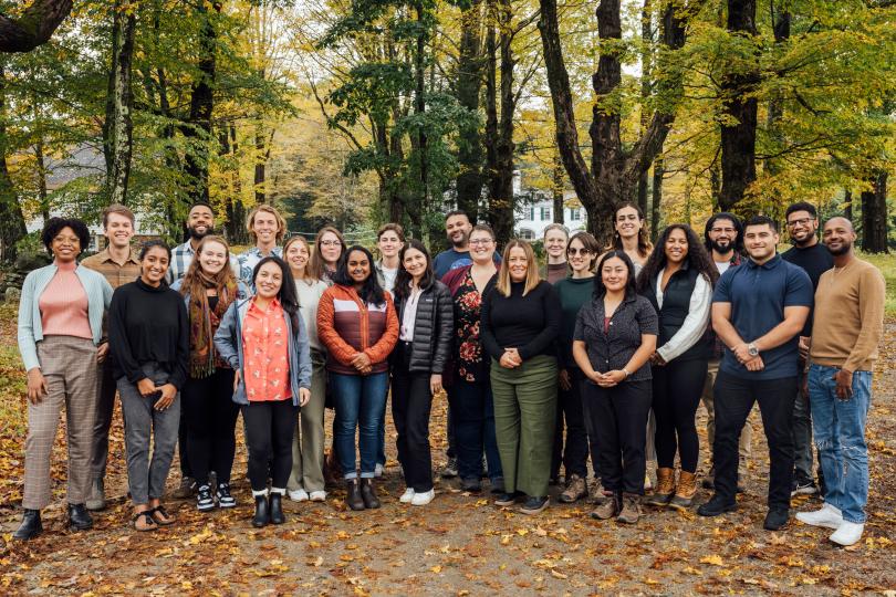 Switzer Fellows and staff at the 2023 Fall Retreat, standing in front of large trees and on a path littered with fall leaves.