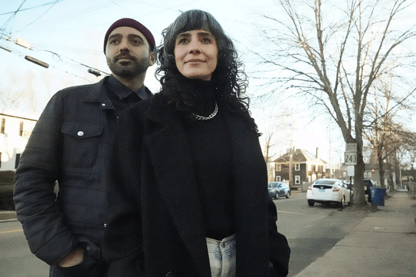 Bruni and David Pizarro stand on a street with a tree in the background