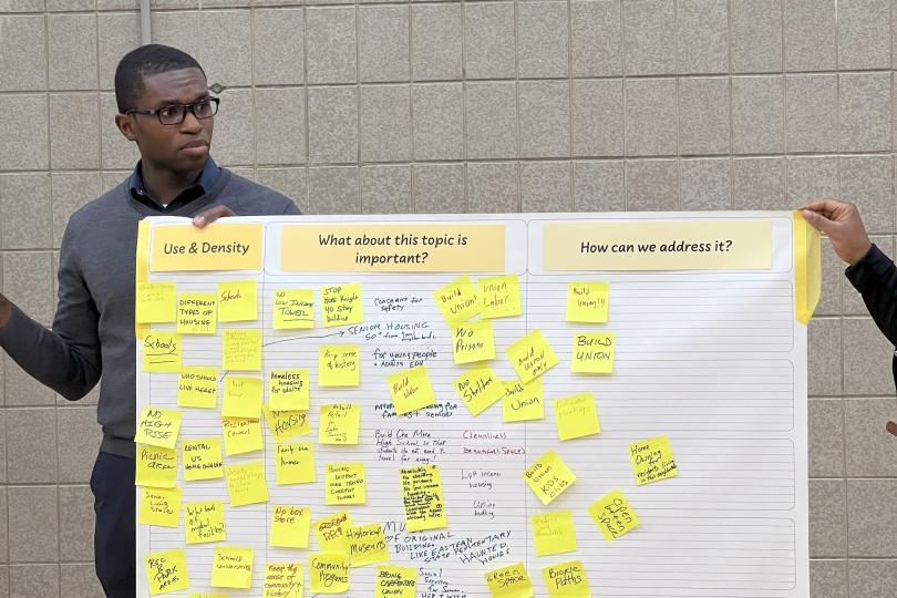 Doug McPherson holds a poster full of post it notes at a community meeting.