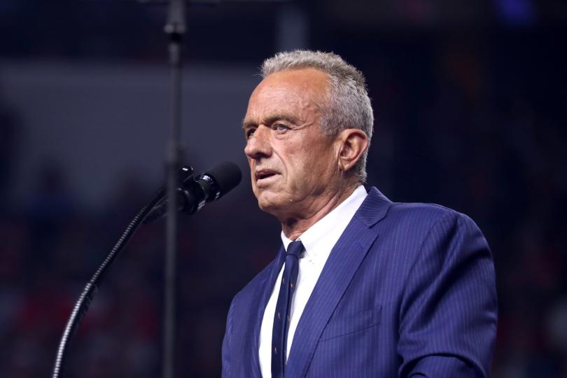 Robert F. Kennedy, Jr. stands at a podium speaking into a microphone. 