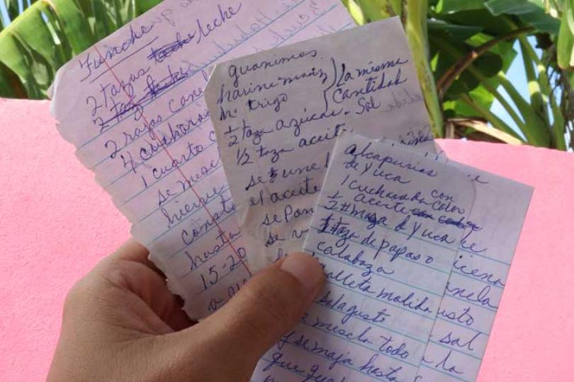 Luis holds pages from the notebook of traditional Puerto Rican recipes his grandmother shared with him.