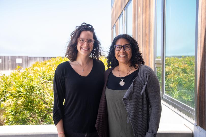 Melissa Cronin and Erika Zavaleta stand on a sunny balcony