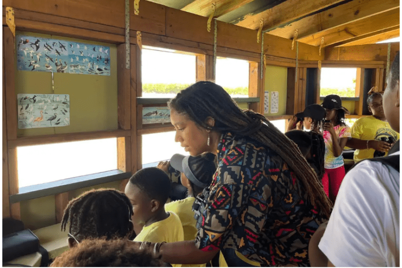 Olivia Walton stands with a group of students in a bird watching blind.