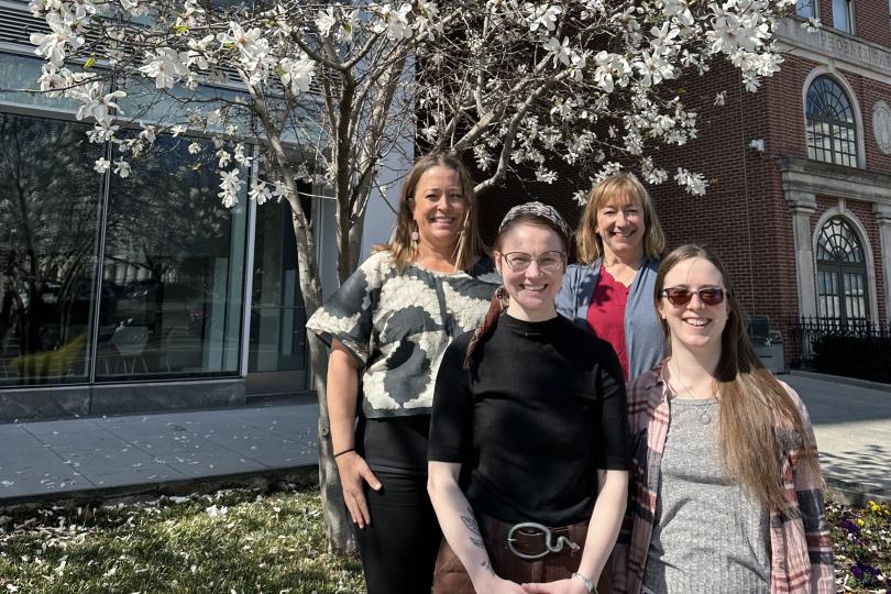 Switzer Foundation staff are smiling and standing in front of a blooming flower tree