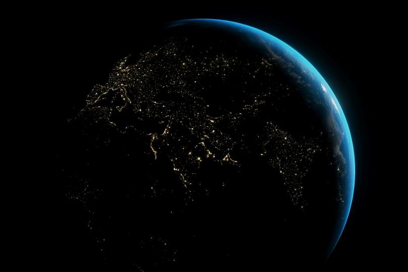 A view of the earth from space at night above Africa, Europe and India, with a blue glow on the right side of the globe. 