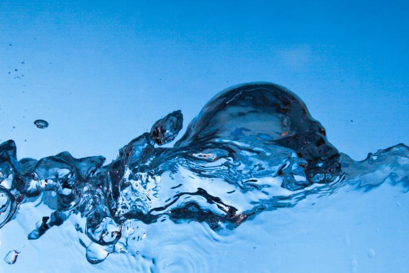 A close up of a wave of clear water on a blue background