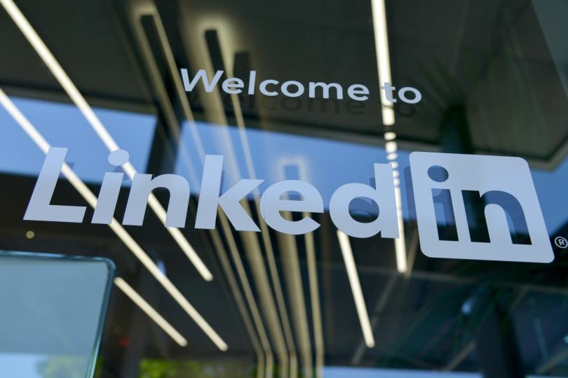 A glass window with the text "Welcome to LinkedIn" written in white. The reflection of lightbulbs can be seen in the glass. 