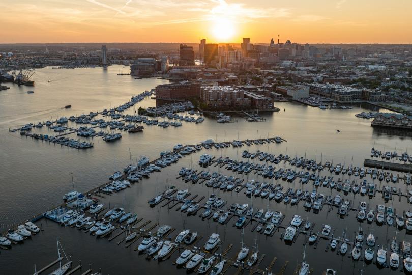 Sunshine over the Baltimore Harbor full of sailboats against an urban skyline. 