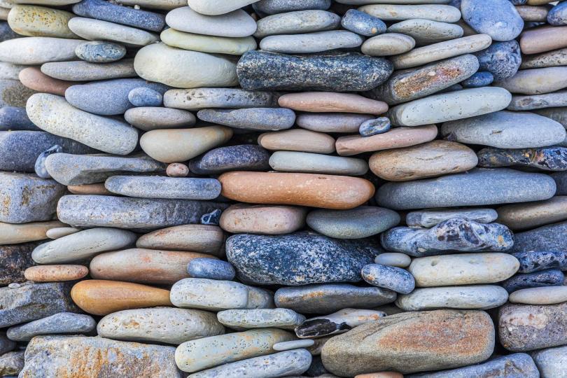a wall of naturally colorful weathered stones stacked on top of each other