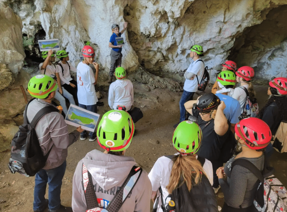 People in hard hats stand listening to a guide in the caves, which feature rock art and petroglyphs.