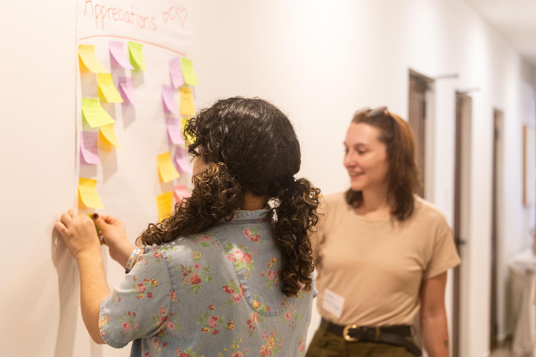 Karen Diaz and Sydney Clements add notes to an “Appreciations” chart that was added to throughout the weekend