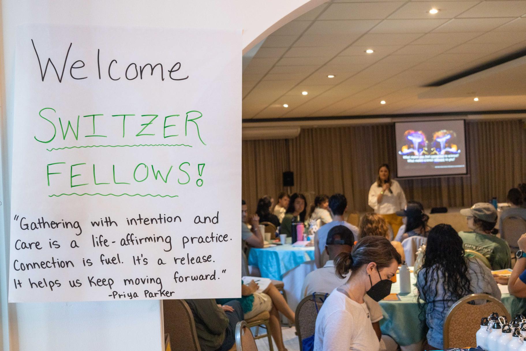 “Gathering with intention and care is a life-affirming practice. Connection is fuel. It’s a release. It helps us keep moving forward.” - Priya Parker. A sign welcomes Switzer Fellows to the gathering with this quote while Mónica Feliú Mójer speaks with the group.